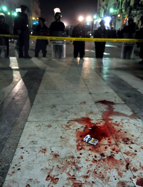 epa01644614 The ground is bloodstained as Egyptian police stand guard outside the Al-Husseini mosque in the Khan el-Khalili market following a bomb blast in Cairo, Egypt on 22 February 2009. A bomb th ...