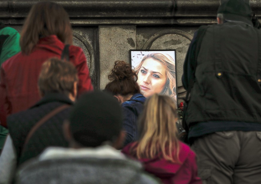 A portrait of slain television reporter Viktoria Marinova is placed on the Liberty Monument, as people wait to place flowers and candles during a vigil in Ruse, Bulgaria, Monday, Oct. 8, 2018. Bulgari ...