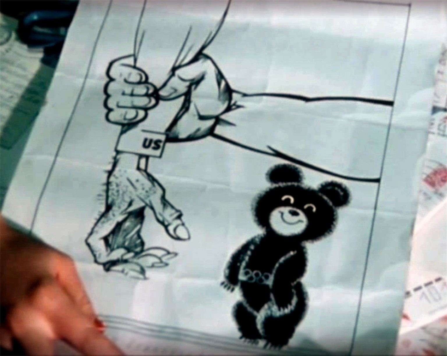 Soviet cartoon of the US Olympic boycott.  A Soviet arm protects 'Misha', the innocent Olympics mascot, from American access.  Fragment from the Rundschau contribution ...