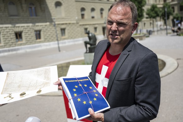 SVP Nationalrat Marcel Dettling, SZ, SVP Praesident, haelt einen geschnuerten Stapel Papier, welcher die Vertraege mit der EU repraesentieren soll, sowie eine Kopie des Bundesbriefs, um gegen die Vert ...