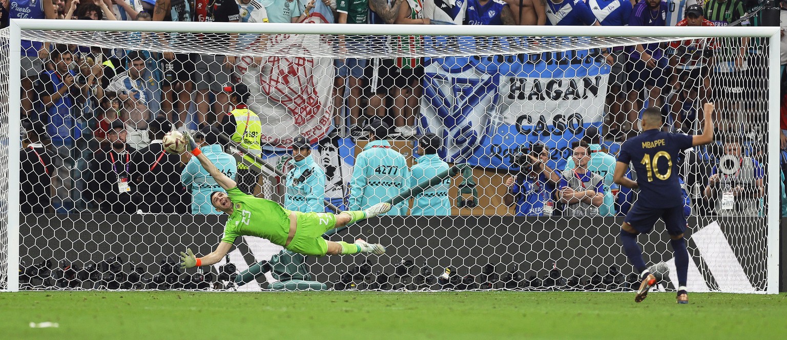 epa10372882 Kylian Mbappe (R) of France scores against Argentina&#039;s goalkeeper Emiliano Martinez (L) during the penalty shoot-out of the FIFA World Cup 2022 Final between Argentina and France at L ...