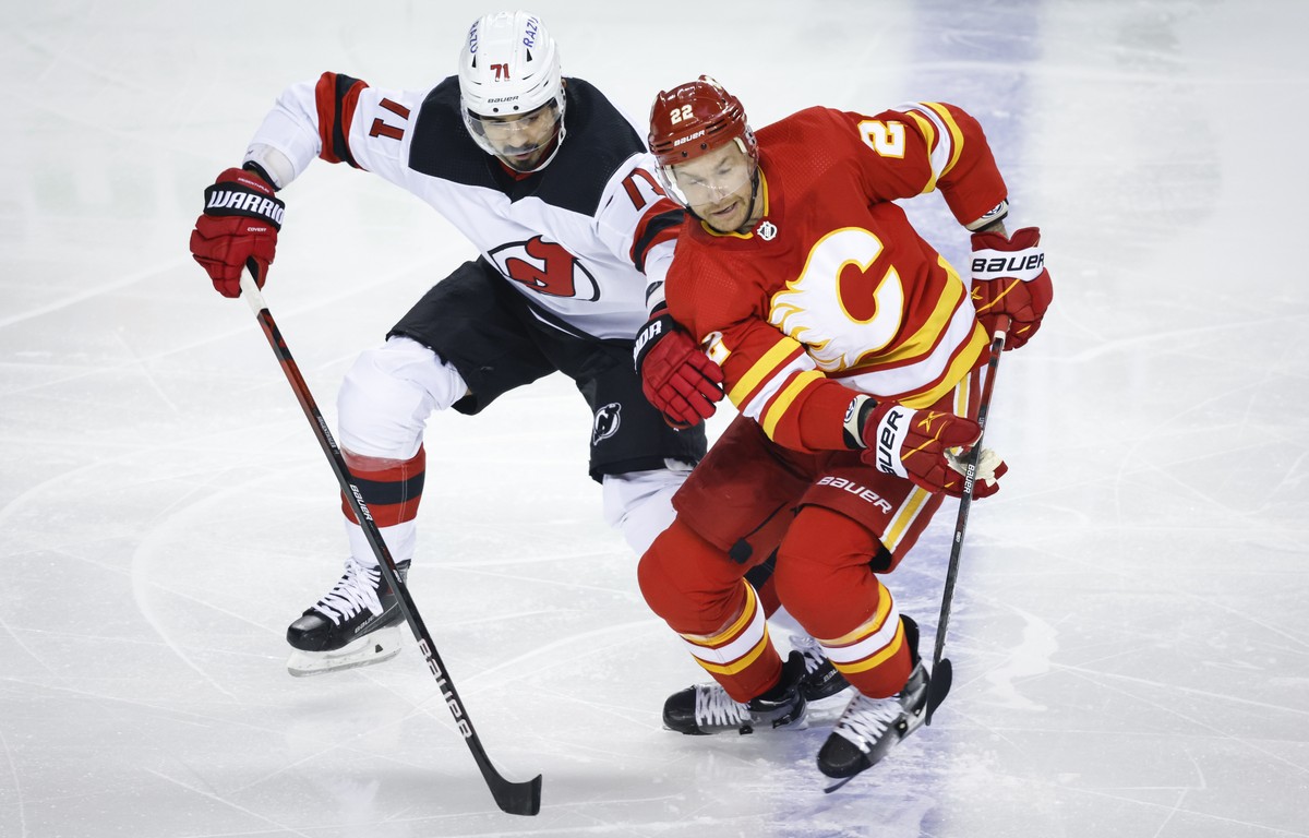 New Jersey Devils' Jonas Siegenthaler, left, grabs Calgary Flames' Trevor Lewis during the first period of an NHL hockey game Wednesday, March 16, 2022, in Calgary, Alberta. (Jeff McIntosh/T ...
