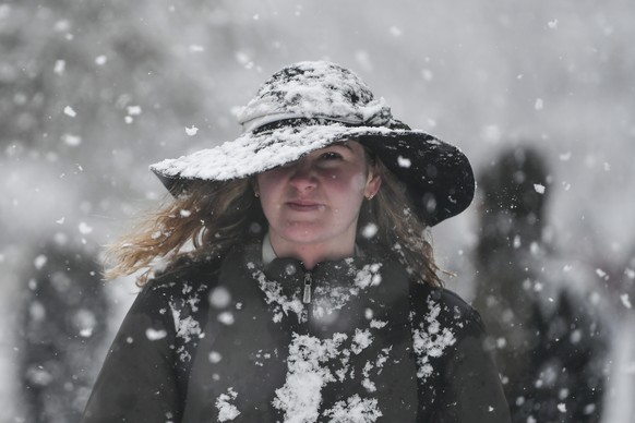 A woman wearing a hat walks during a snowfall, in central Athens, on Monday, Jan. 24, 2022. A severe weather front has hit Greece, with sub-freezing temperatures and snowfall in many parts of the coun ...