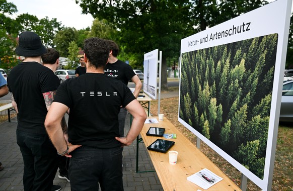 epa10753727 Tesla workers speak with local residents during Tesla Gigafactory promoting event at Hangelsbeg near Berlin, Germany, 18 July 2023. Tesla plans to expand its Gigafactory by doubling produc ...