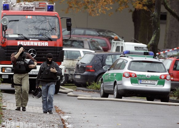 Einsatzkraefte der Polizei gehen am Montag, 20. Nov. 2006, in Emsdetten durch den abgesperrten Bereich um eine Schule. Ein toter Amoklaeufer und acht Verletzte: Das ist die Bilanz eines blutigen Ueber ...