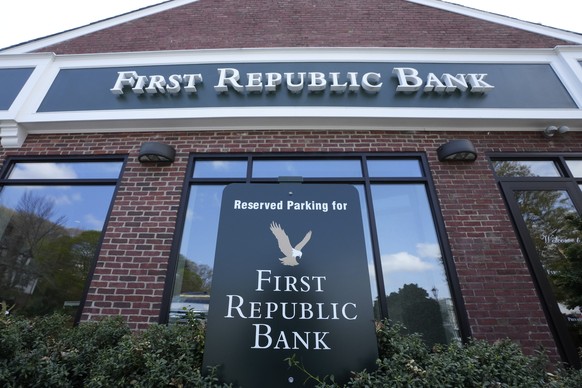 First Republic Bank signs and logos rest near a parking space, below, and on the exterior of a bank branch location, above, Wednesday, April 26, 2023, in Wellesley, Mass. First Republic Bank&#039;s st ...