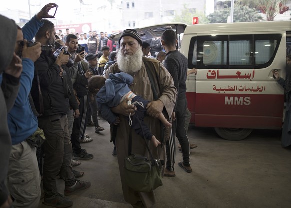epa11011555 A man carries a baby as people wounded in Israeli air strikes on southern Gaza arrive at Nasser Hospital in Khan Yunis, southern Gaza Strip, 05 December 2023. Israeli forces resumed milita ...