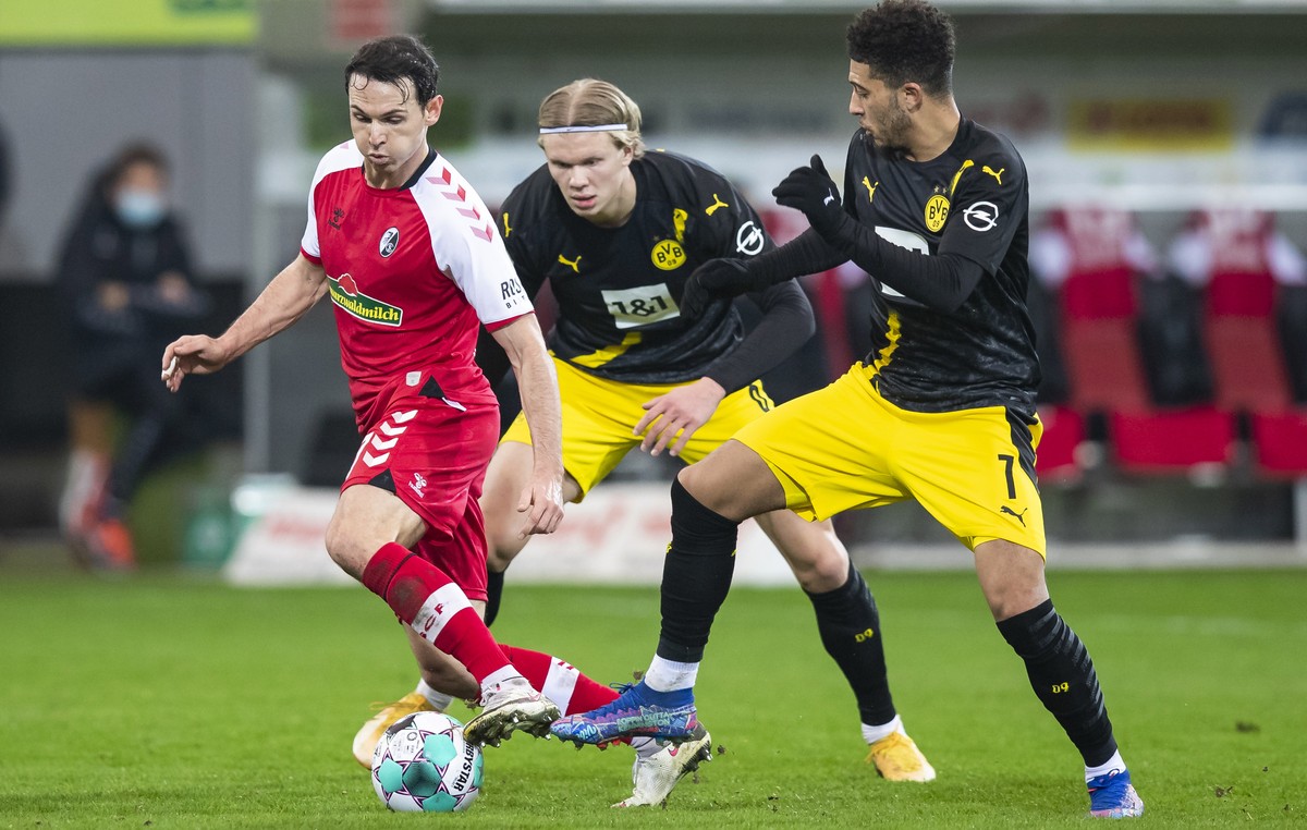 Freiburg's Nicolas Höfler, left, in action against Dortmund's Erling Haaland and Jadon Sancho, right, during their German Bundesliga soccer match at Schwarzwald-Stadion in Freiburg, Germany, ...