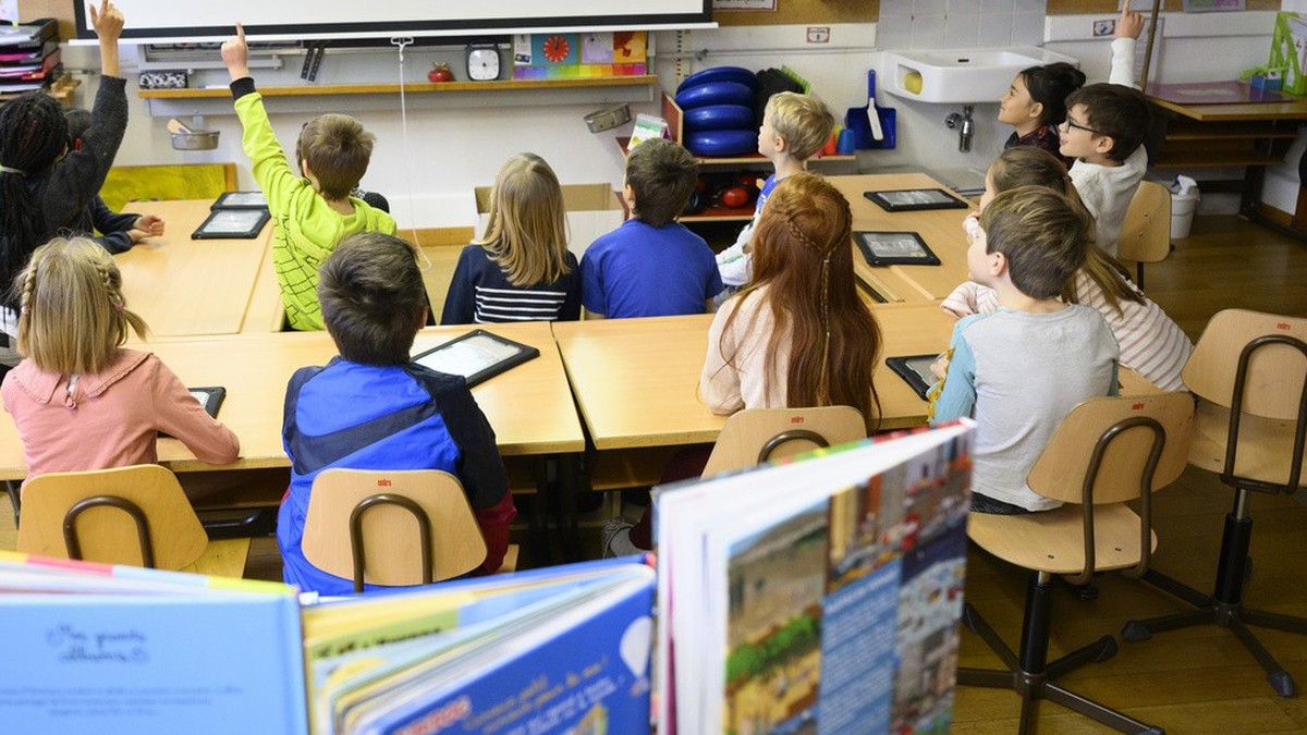 Des eleves de 4eme annee primaire, 4P, de 7-8 ans suivent a l'aide d'une tablette un cours dans la classe de l'enseignante Line Moita, gauche, d'education numerique de l'ecole ...