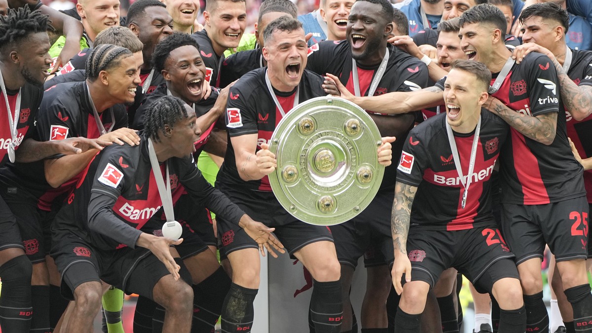 Leverkusen's Granit Xhaka, centre, celebrates with the trophy as his team won the German Bundesliga soccer match between Bayer Leverkusen and FC Augsburg at the BayArena in Leverkusen, Germany, S ...