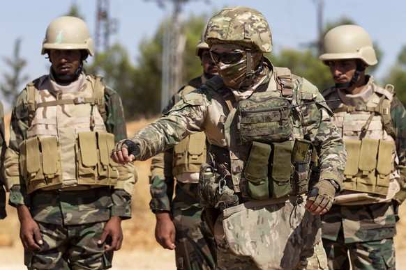 A masked Russian military adviser, foreground, gestures as he speaks to Syrian soldiers during military exercises at a base about 50-kilometers away from Damascus, Syria, Tuesday, Sept. 24, 2019. (AP  ...