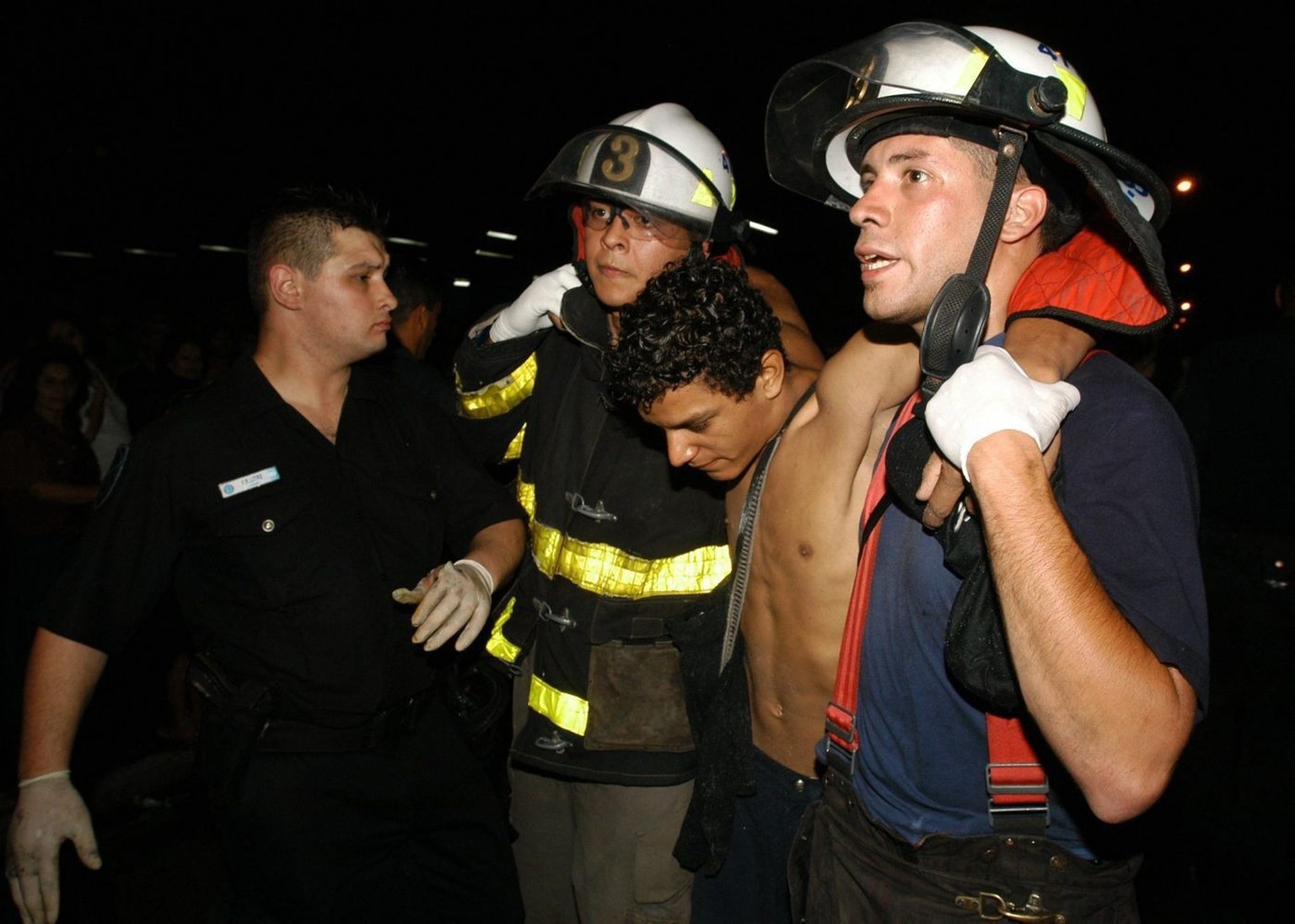 A young man with symptoms of asphyxia is carried by two firemen outside nightclub 'Republica de Cromagnon' in Buenos Aires, Friday 31 December 2004. A fire at the dance club killed at least  ...