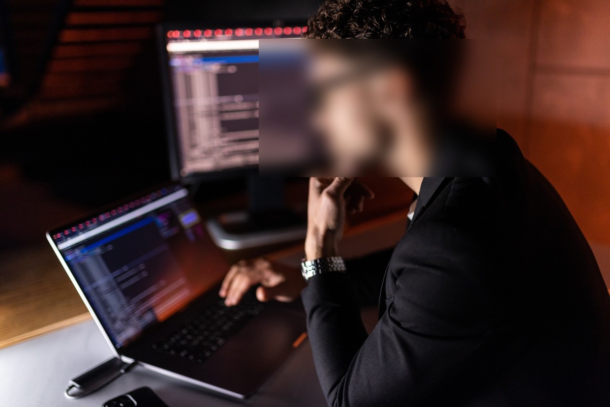 Junger Mann vor Laptop, Gesicht verpixelt. Symbolbild für Überwachung.
