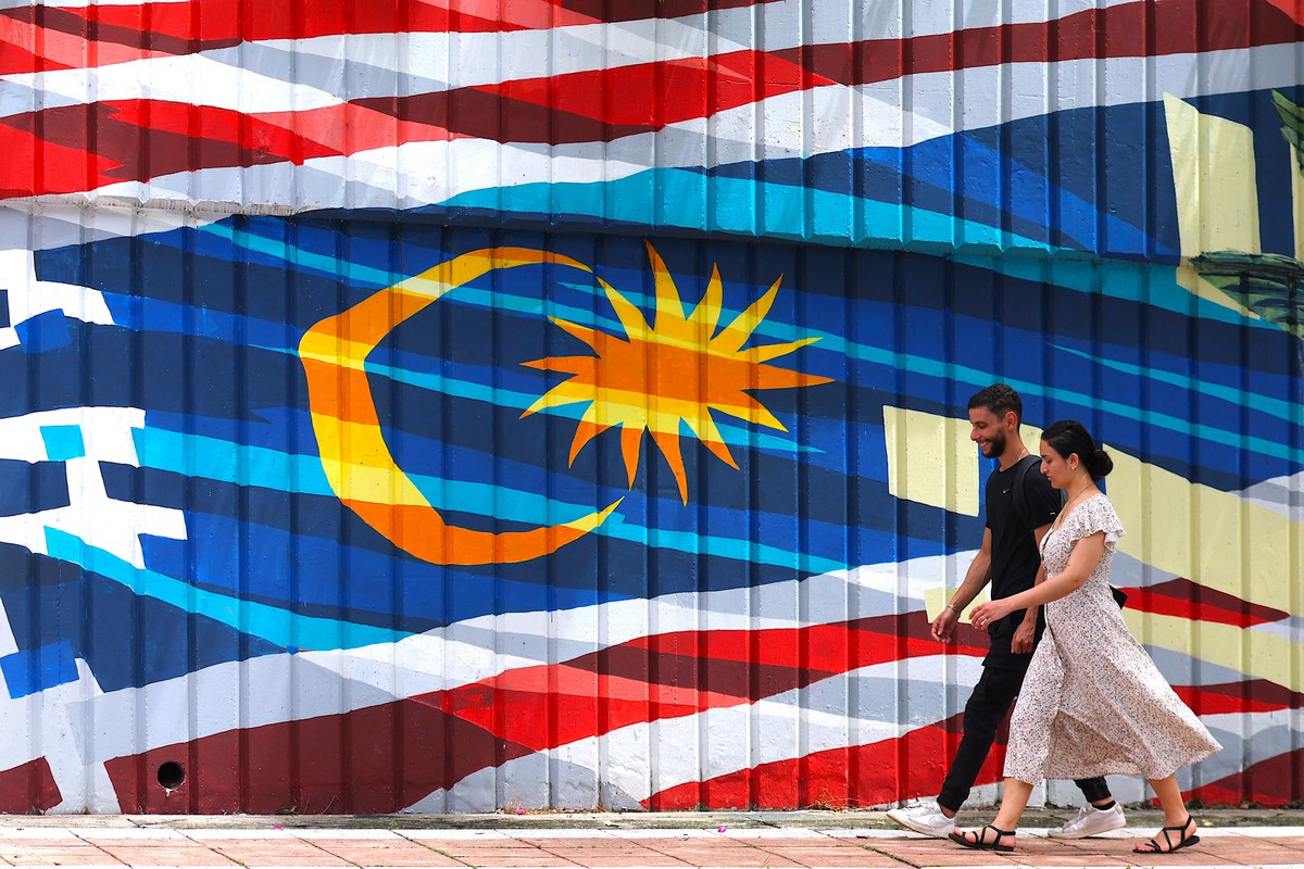 epaselect epa12015147 A couple pass by a mural of the Malaysian national flag in Kuala Lumpur, Malaysia, 07 April 2025. "Malaysia will seek an ASEAN response to US President Donald Trump's t ...