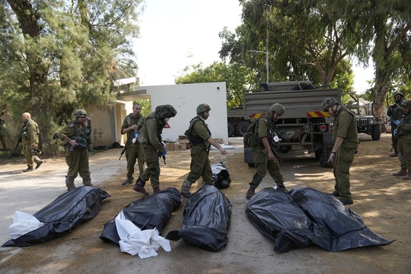 Israeli soldiers stand next to the bodies of Israelis killed by Hamas militants in kibbutz Kfar Azza on Tuesday, Oct. 10, 2023. Hamas militants overran Kfar Azza on Saturday, where many Israelis were  ...