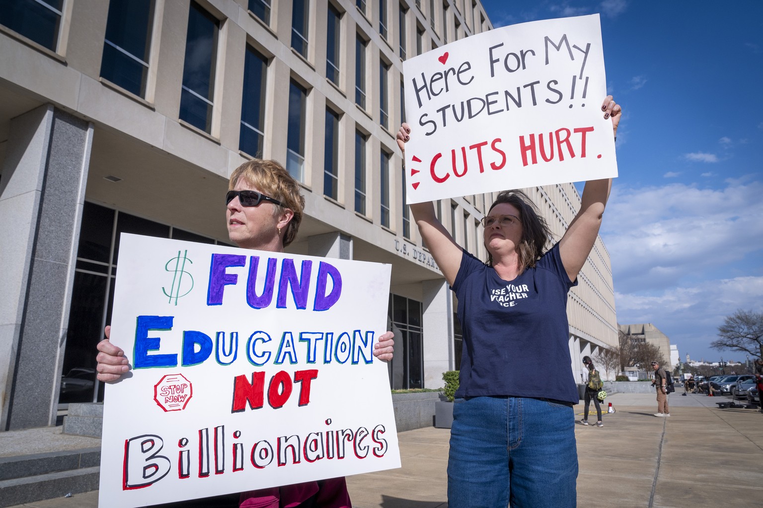 High School teacher June Kelly, left, and SJ Marcotte, right, who teaches business leadership, both with a group of educators from Vermont, hold signs in support of the Department of Education, Thursd ...