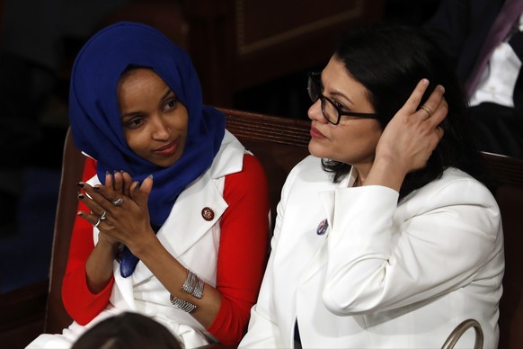 Rep. Ilhan Omar, D-Minn., left, and Rep. Rashida Tlaib, D-Mich., right, listen as President Donald Trump delivers his State of the Union address to a joint session of Congress on Capitol Hill in Washi ...