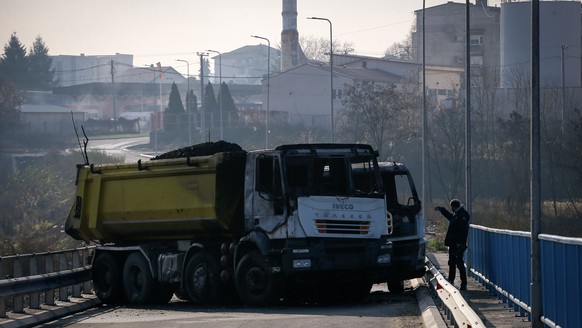 A man takes photos of a burnt-out truck, part of a barricade on the bridge near the northern, Serb-dominated part of ethnically divided town of Mitrovica, Kosovo, Thursday, Dec. 29, 2022. Serbia&#039; ...