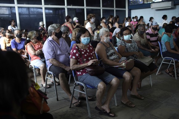 Women wait to to be inoculated with a dose of the Sinovac COVID-19 vaccine, in Sao Joao de Meriti, Rio de Janeiro state, Brazil, Wednesday, April 28, 2021. (AP Photo/Silvia Izquierdo)