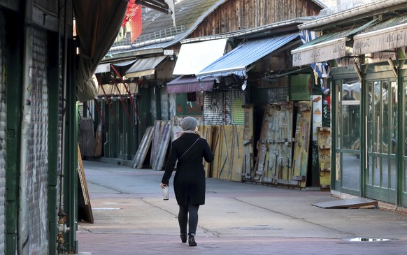 A woman walks through a closed market in downtown Vienna, Austria, Saturday, Dec. 26, 2020. The Austrian government has moved to restrict freedom of movement for people, in an effort to slow the onset of the COVID-19 coronavirus. (AP Photo/Ronald Zak)