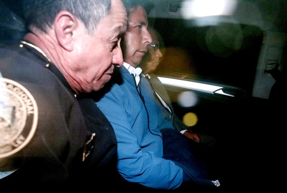 epa10354340 The deposed president of Peru Pedro Castillo (C) is held in a police vehicle in Lima, Peru, December 7, 2022. Castillo was arrested on Wednesday and is at the police station of the Li...