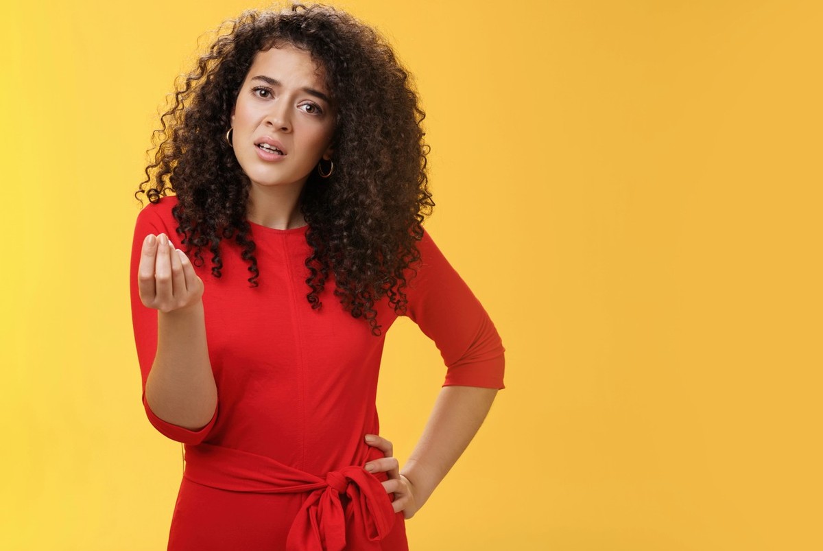 Girl being pissed off arguing ad complaining making italian what do you want gesture looking bothered waiting for explanation as standing annoyed and fed up over yellow background. Negative emotions