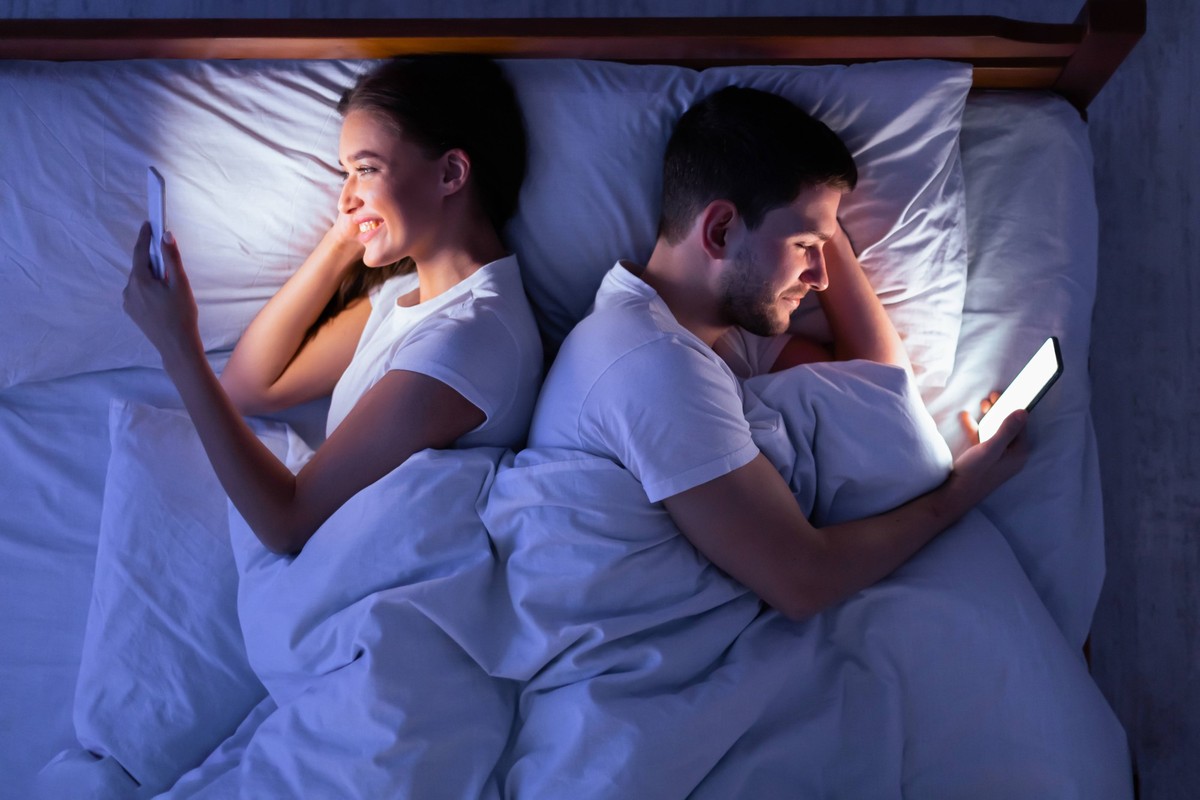 Couple Texting On Phones Lying Back-To-Back In Bed, Above View Cheating. Young Couple Texting On Phones Lying Back-To-Back In Bed At Night. Above View, Low Light, model released, , 62285766.jpg RECORD ...