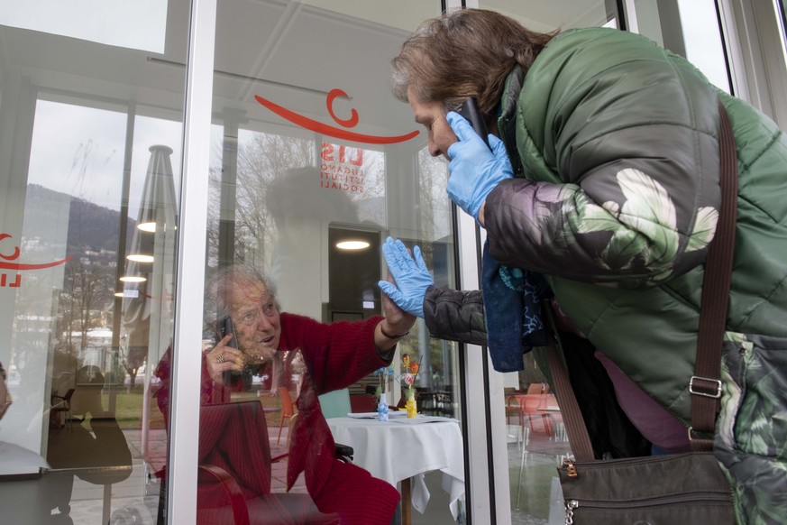 Monica telefoniert durch eine Scheibe mit ihrer 88-jaehrigen Mutter Giuseppina, am Mittwoch, 1. April 2020, im Altersheim Serena in Lugano. Aufgrund des Coronavirus wird ein direkter Kontakt vermieden ...