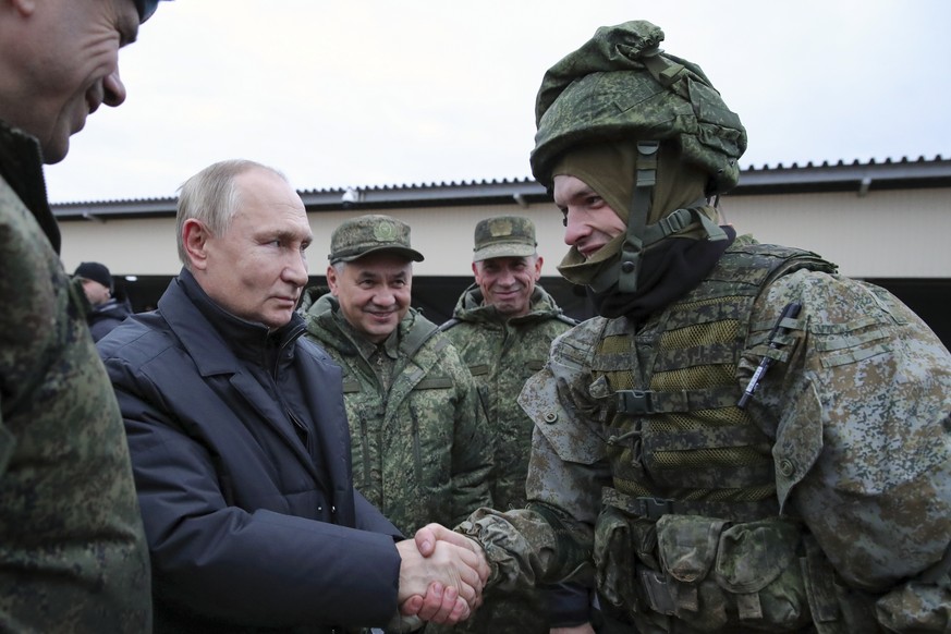 FILE - Russian President Vladimir Putin shakes hands with a soldier as he visits a military training centre of the Western Military District for mobilised reservists as Russian Defense Minister Sergei ...