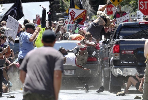 FILE - In this Aug. 12, 2017, file photo, people fly into the air as a vehicle drives into a group of protesters demonstrating against a white nationalist rally in Charlottesville, Va. Efforts to take ...