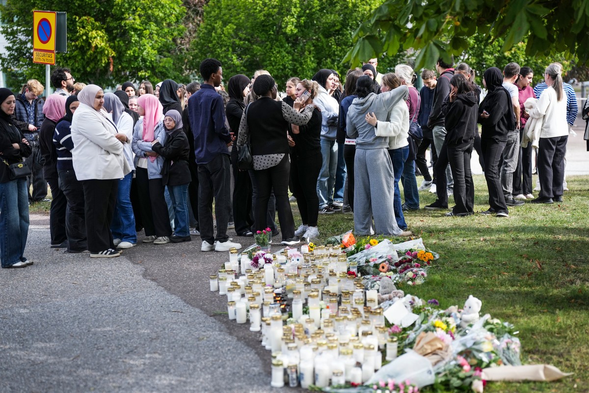 People leave flowers and candles at a makeshift memorial outside a school in Fagersta, Sweden, Saturday Aug. 22, 2026, the day after an 18-year-old with a sword attacked the school killing one person  ...