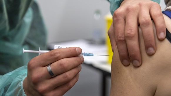 Ein Durchdienersoldat der Sanitaetsschule Airolo verabreicht eine Booster-Impfung mit dem Covid-19-Impfstoff im Impfzentrum in Delemont, am Dienstag, 14. Dezember 2021. (KEYSTONE/Georgios Kefalas)