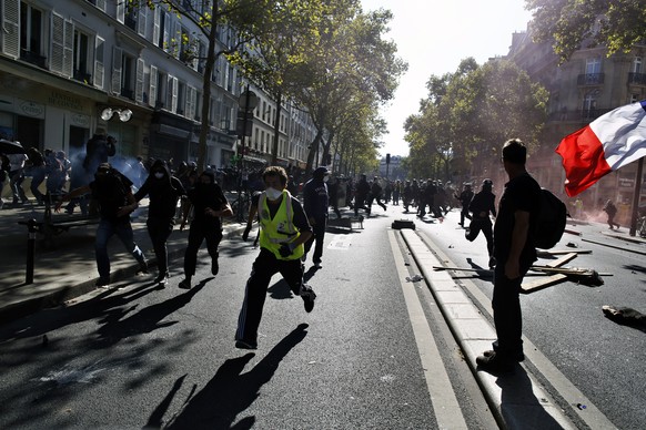 Protestors run away from riot police during a climate demonstration, in Paris, Saturday, Sept. 21, 2019. Scuffles broke out in Paris between some violent activists and police which responded with tear ...