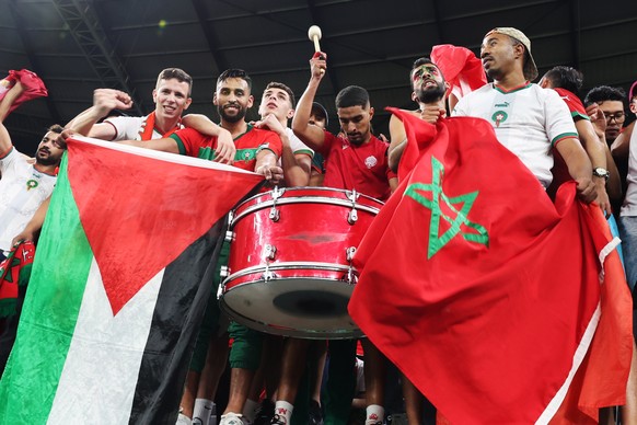 epa10352387 Fans of Morocco cheer while one holds a flag of Palestine (L) after the FIFA World Cup 2022 round of 16 soccer match between Morocco and Spain at Education City Stadium in Doha, Qatar, 06  ...