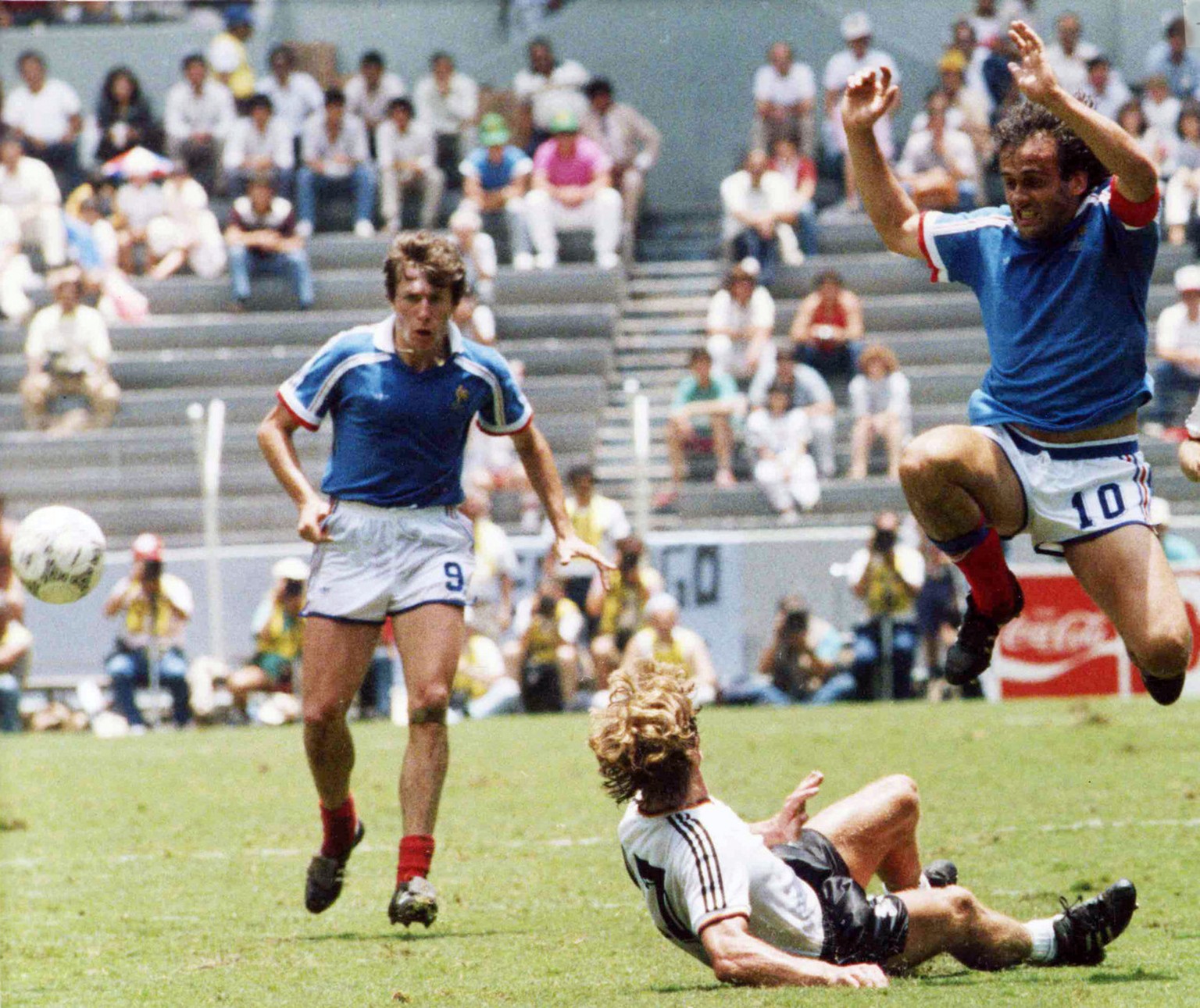France's Michel Platini, right, jumps over Germany's Ditmar Jakobs during the Football World Cup Semi-Final in Guadalajara, Mexico, on June 25, 1986. French defender Luis Fernandez, left, wa ...