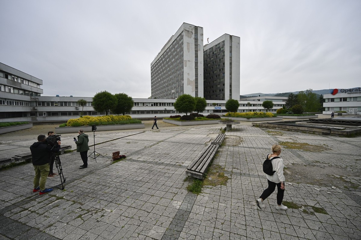 A woman walks next to camera news crew outside the F. D. Roosevelt University Hospital, where Slovak Prime Minister Robert Fico, who was shot and injured, is treated, in Banska Bystrica, central Slova ...