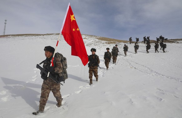 Soldiers march with a Chinese flag during field exercises in the snow near the Kunjerab Pass bordering Pakistan in Taxkorgan in northwest China&#039;s Xinjiang Uyhgur Autonomous Region on Jan. 6, 2021 ...