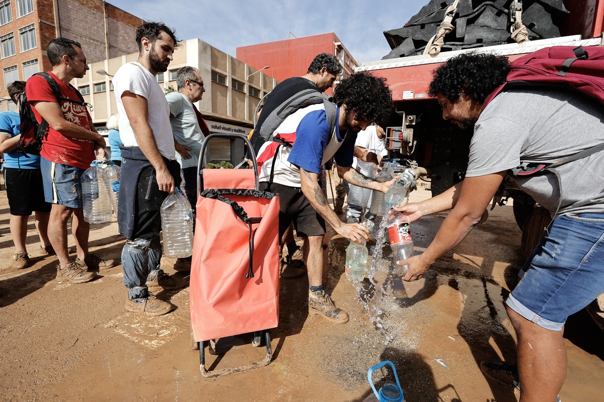 epa11694062 People queue up for drinking water supplies in the flood-hit municipality of Paiporta, in the province of Valencia, Spain, 31 October 2024. Emergency services continued to clear debris a d ...