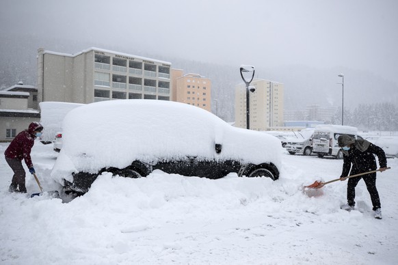 Zwei Maenner schaufeln den Schnee bei einem Auto weg bei starkem Schneefall in St. Moritz am Samstag, 5. Dezember 2020. (KEYSTONE/Alexandra Wey)..