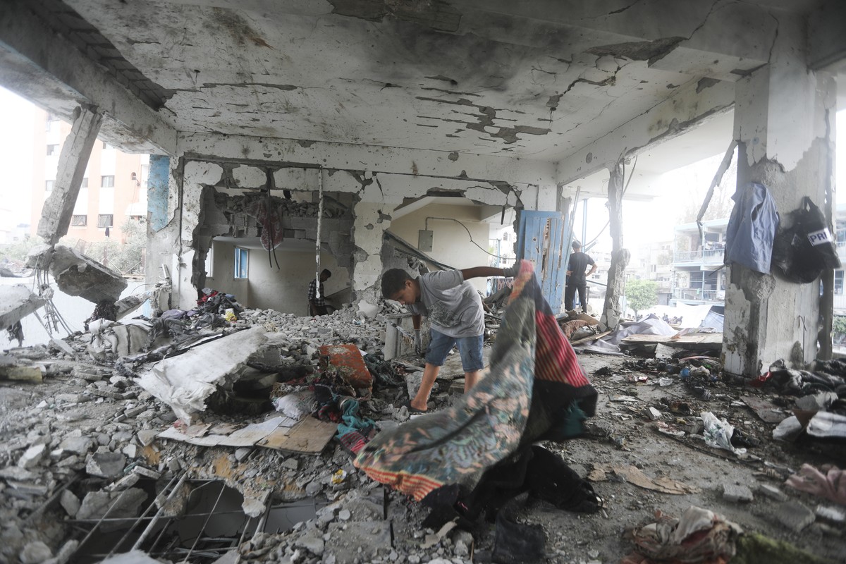 Palestinians look at the aftermath of the Israeli strike on a U.N.-run school that killed dozens of people in the Nusseirat refugee camp in the Gaza Strip, Thursday, June 6, 2024. (AP Photo/Ismael Abu ...