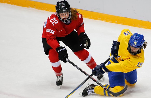 Maria Lindh of Sweden (19) takes control of the puck from Livia Altmann of Switzerland (22) during the first period of the women&#039;s bronze medal ice hockey game at the 2014 Winter Olympics, Thursd ...