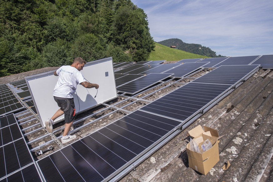 Der Solateur Jonas Huerlimann bei der Montage einer Solaranlage auf einer privat und gewerblich genutzten Halle in Stans, Kanton Nidwalden, am Donnerstag, 14. Juli 2022. Die Solaranlage hat eine Groes ...