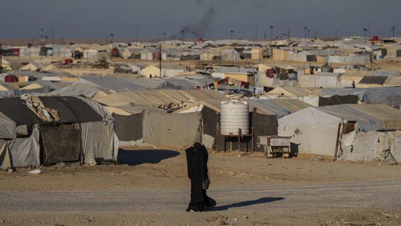 FILE - A woman walks in the al-Hol camp in northeastern Syria's Hasakeh province, where tens of thousands of mostly women and children linked to the Islamic State group have been living for years ...