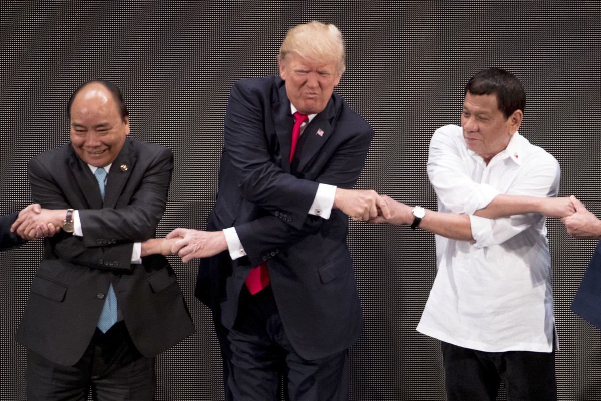 CORRECTS ID TO VIETNAMESE PRIME MINISTER NGUYEN XUAN PHUC - U.S. President Donald Trump, center, reacts as he does the "ASEAN-way handshake" with Vietnamese Prime Minister Nguyen Xuan Phuc,  ...