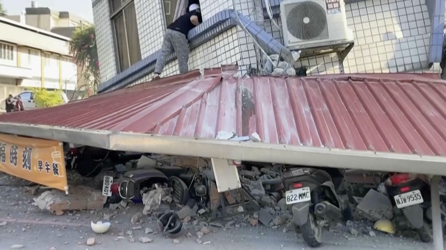 In this image taken from a video footage run by TVBS, a man checks a partially collapsed building in Hualien, eastern Taiwan on Wednesday, April 3, 2024. A powerful earthquake rocked the entire island ...