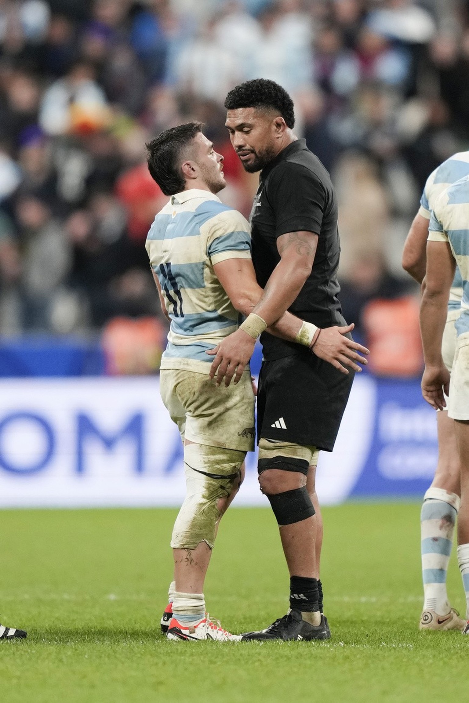 New Zealand's Mark Telea, right, and Argentina's Juan Martin Gonzalez hug at the end of the Rugby World Cup semifinal match between Argentina and New Zealand at the Stade de France in Saint- ...