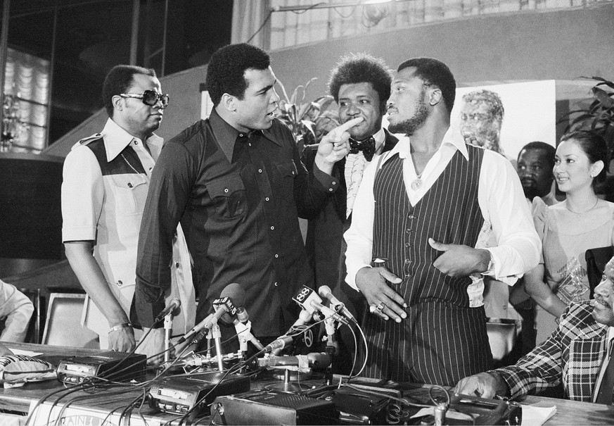 FILE - In this July 17, 1975, file photo, heavyweight champion Muhammad Ali, left, points at challenger Joe Frazier at a news conference in New York City. Standing between the fighters is boxing promo ...