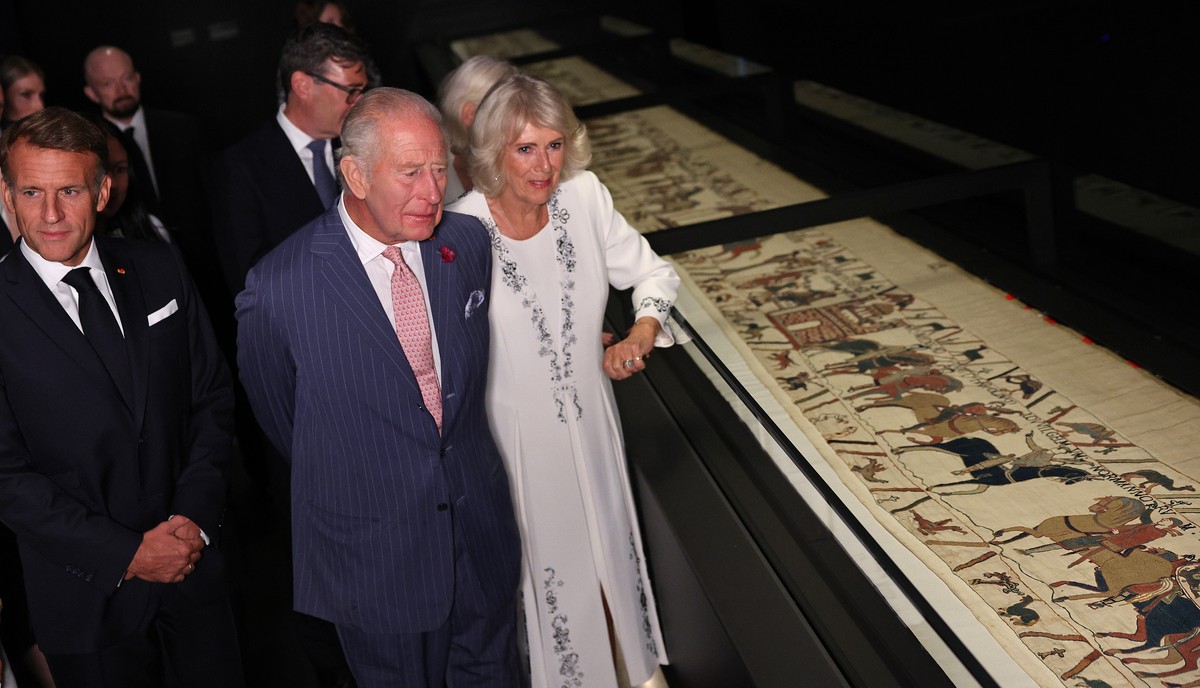 Britain's King Charles III, center, and France's President Emmanuel Macron, left, accompanied by their wives, Queen Camilla, right, and Brigitte Macron, obscured, view sections of the Bayeux ...