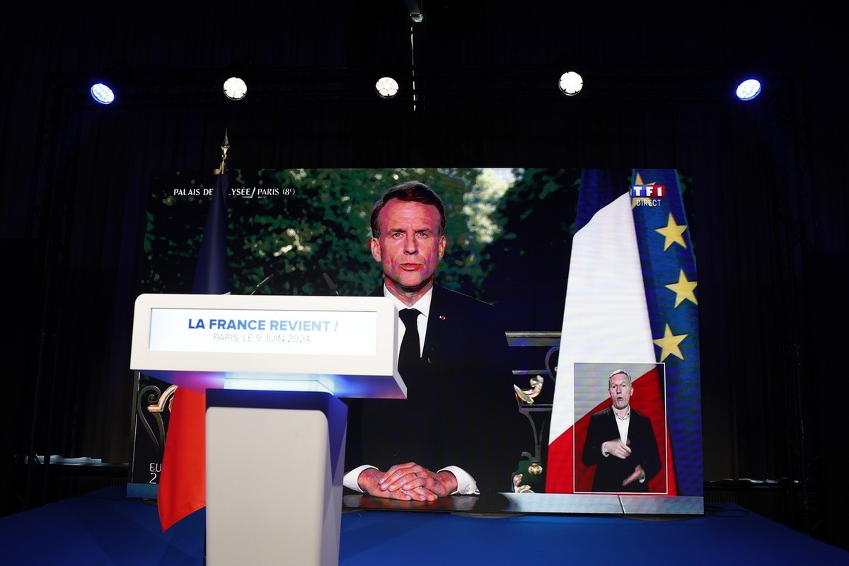 epa11400683 French President Emmanuel Macron is displayed on a large screen during a televised address to the nation, at the electoral party of the French right-wing party National Rally (Rassemblemen ...