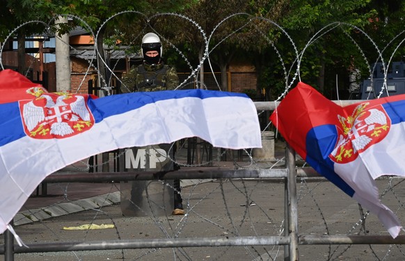 epa10666280 Serbian flags fly on a fence in front of a soldier of the Polish contingent of the NATO-led international peacekeeping Kosovo Force (KFOR) guarding the building of the municipality in Zvec ...